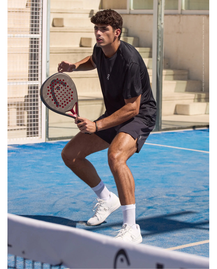 Giocatore di padel in azione, pronto a ricevere, tiene una racchetta Head Coello Pro 2026 su campo azzurro all'aperto.