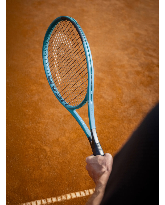 Maestro di tennis: primo piano di una racchetta da tennis azzurra tenuta in mano su campo in terra battuta. Alt text include Hea
